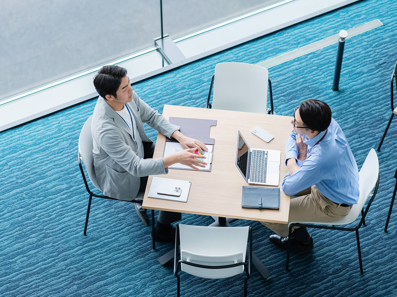 2人の男性が机越しに話し合っている写真